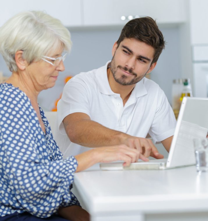 Young,Man,Showing,Elderly,Lady,How,To,Use,Laptop